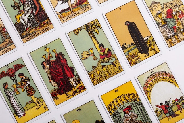 A photograph of several "Minor Arcana" cards from the Rider–Waite Tarot deck. Visible are the Queen of Cups, Knight of Cups, and the 2, 3, 4, 5, 8, 9 and 10 of Cups. All are richly illustrated.