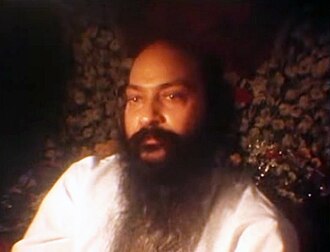 Colour photograph of an Asian man with long black hair and a long beard and moustache.