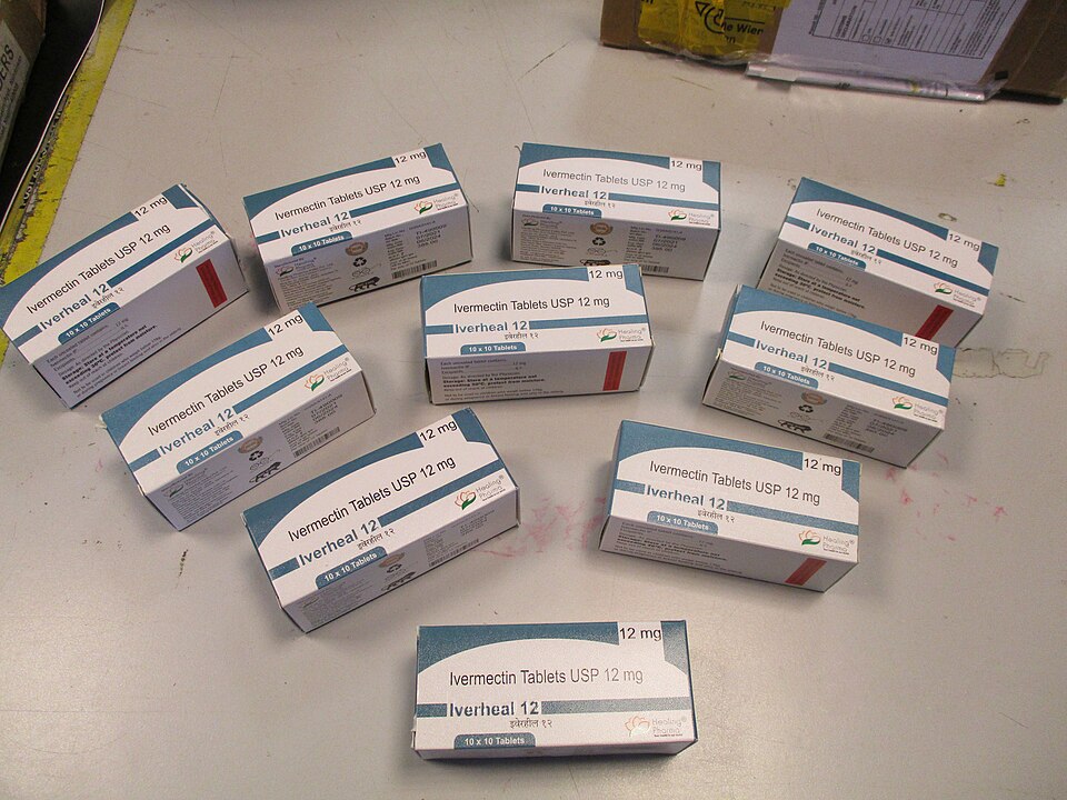 Photograph of a table surface, on which 10 small cardboard boxes are laid out, each printed with "Ivermectin Tablets USP 12mg" and "Iverheal 12"
