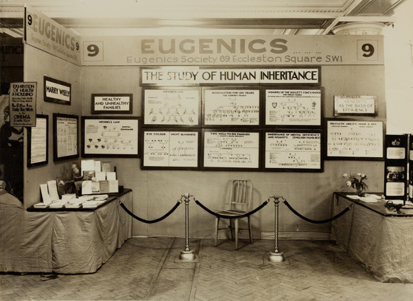 Sepia photograph of a display titled EUGENICS, from the Eugenics Society, displayed in Eccleston Square, south west London in 1930.
Features various family trees under "The study of human inheritance" and title plaques including "Marry wisely", "Healthy and unhealthy families" and "Heredity as the basis of efficiency"