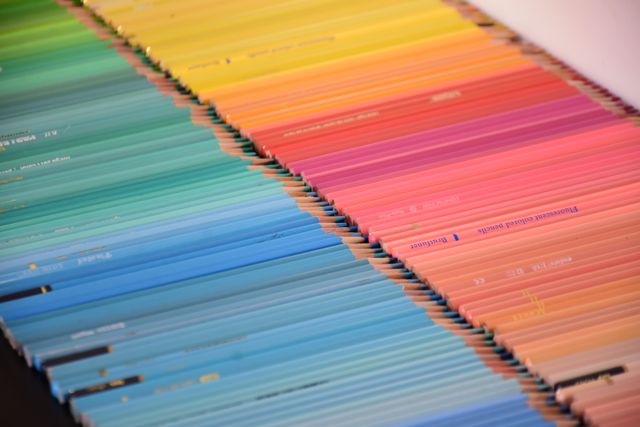 Photograph of many coloured pencils.  One set in various shades of yellow, orange and reds is beside a second set in shades of greens and blues.