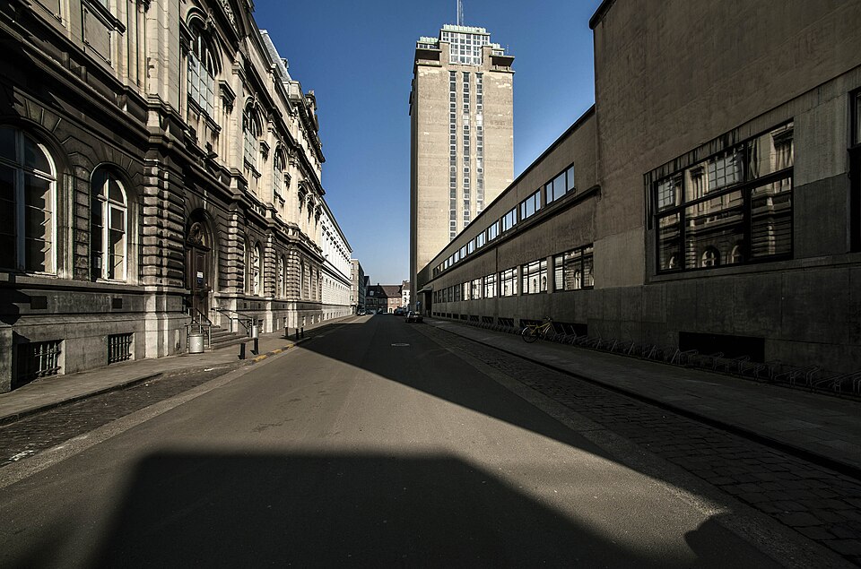 Photograph taken in a city street, with a twenty-storey concrete tower rising behind the buildings in the foreground.