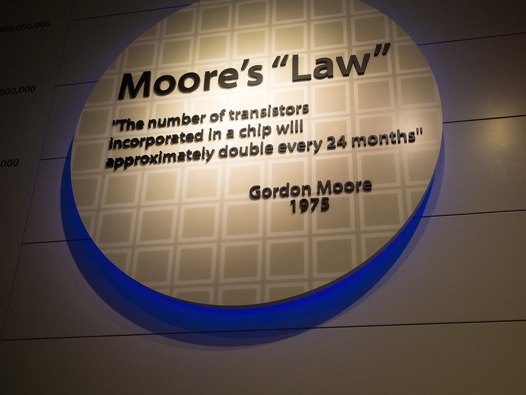 Photograph of a large plaque mounted on a wall. It is circular, and the background is divided into squares resembling chip dies on a silicon wafer. On the plaque is written "Moore's 'Law' –'The number of transistors incorporated in a chip will approximately double every 24 months' Gordon Moore, 1975".