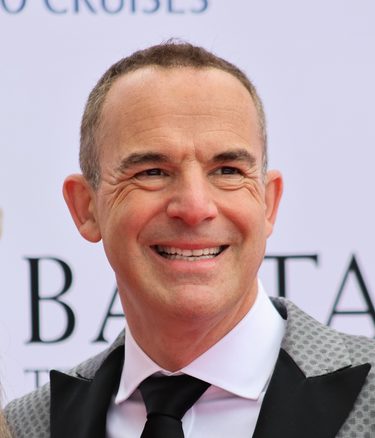 Profile of a smiling Martin Lewis, a white man with short grey/brown hair, wearing a white shirt, black tie and smart black and grey patterned jacket.
https://commons.wikimedia.org/wiki/File:Martin_Lewis_at_BAFTA_2026_02.jpg